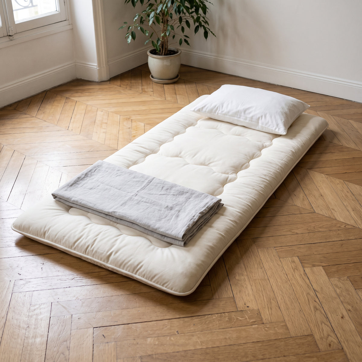 Futon japonais de voyage déplié au sol dans une chambre d'amis